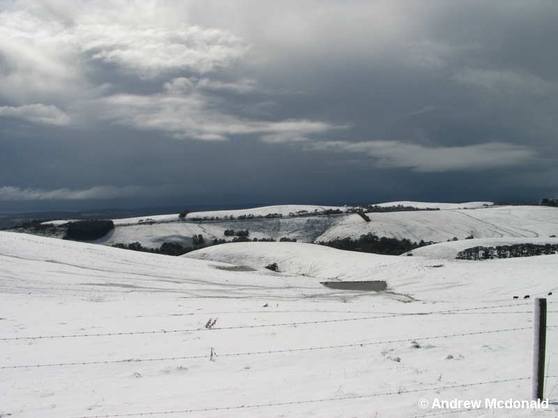 Ominous skies highlight the snow-covered hills.