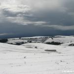 Ominous skies highlight the snow-covered hills.