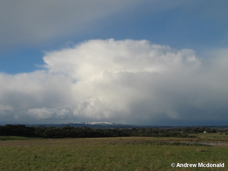 A retreating Cb with snow covered hills.