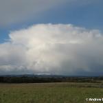 A retreating Cb with snow covered hills.